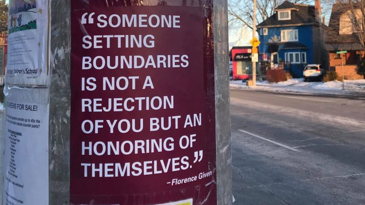 A electricity pole that has various posters attached to it. The key poster is maroon and has the quotation, "Someone setting boundaries is not a rejection of you but an honoring of themselves" as told by Florence Given.