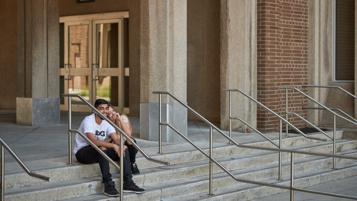 A couple sitting together, laughing on a set of stairs at McMaster University.