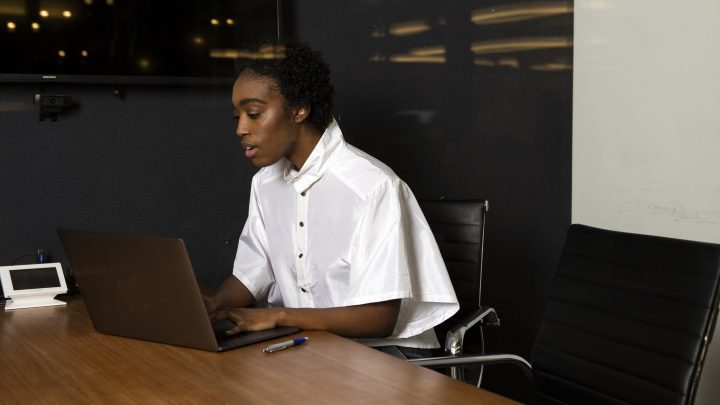 A non-binary person using a laptop at work.